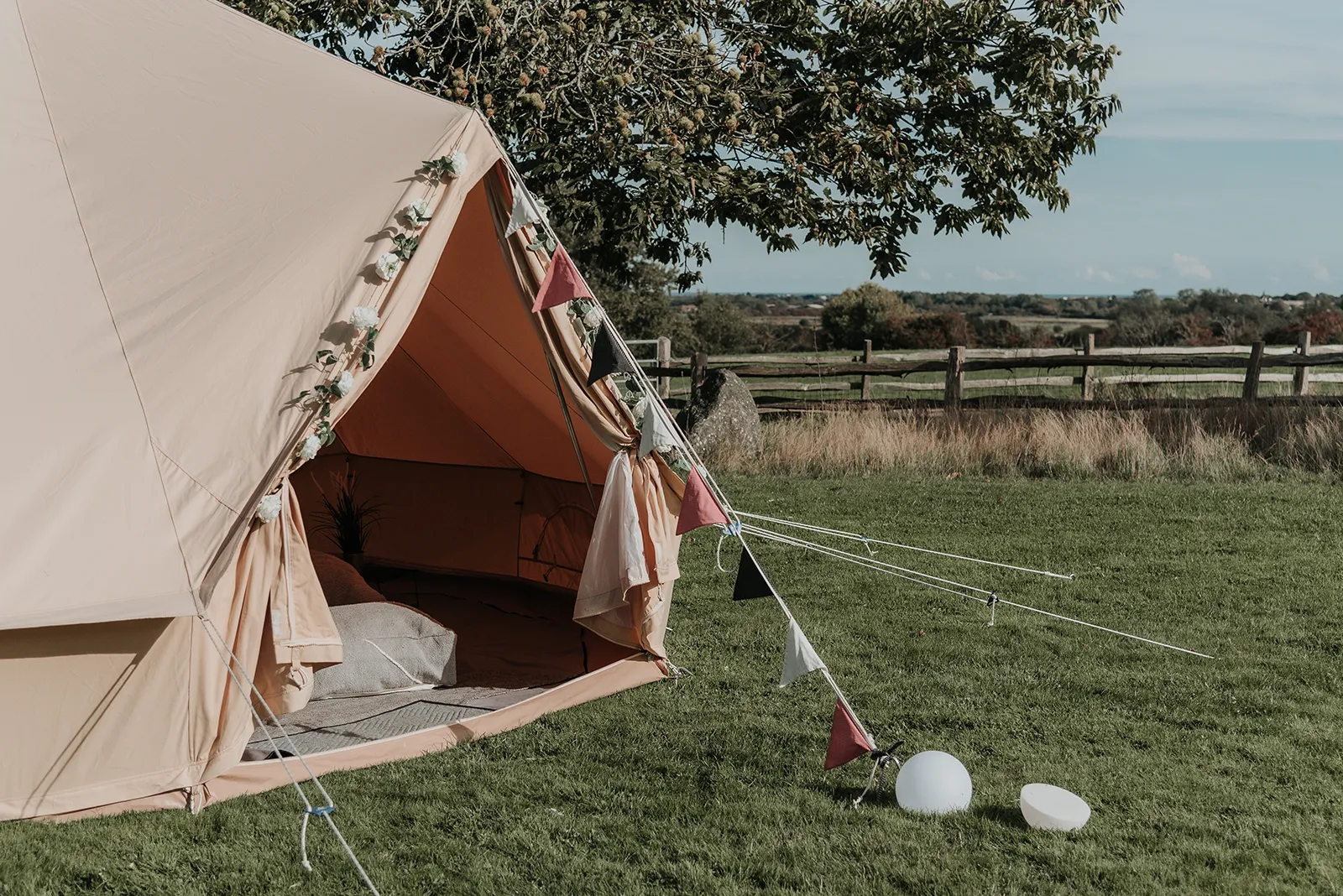 The Beau glamping package, bell tent set up with bunting and soft furnishings.